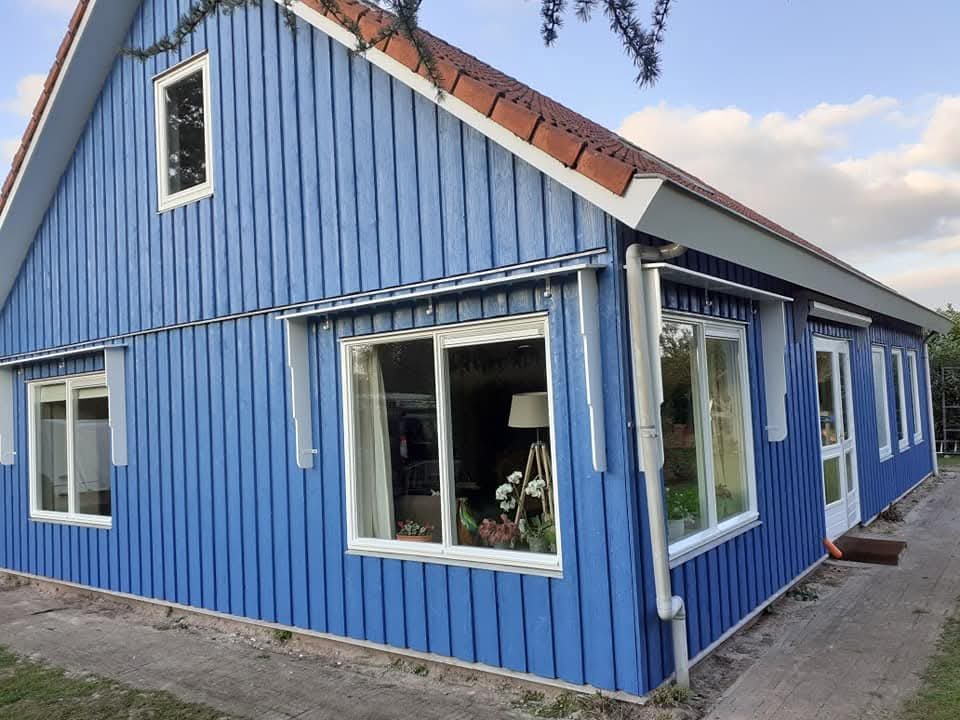 Na: strak blauw geschilderde houten woning